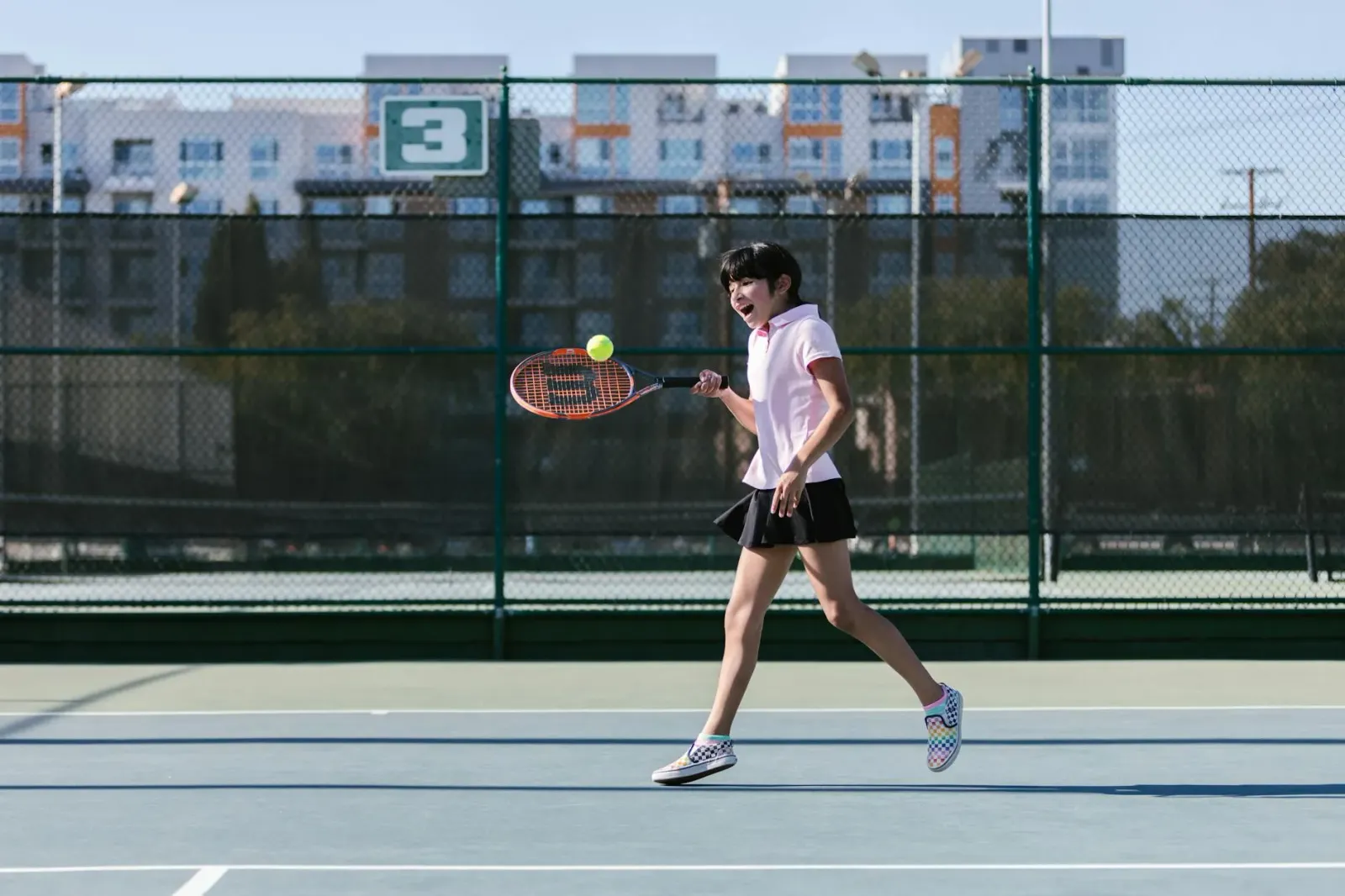 Imajen ida ne'ebé hatudu jogadór tenis furak ho sorrisu surpreza, iha kotuk iha lista muzika no estudante sira iha sala eskol