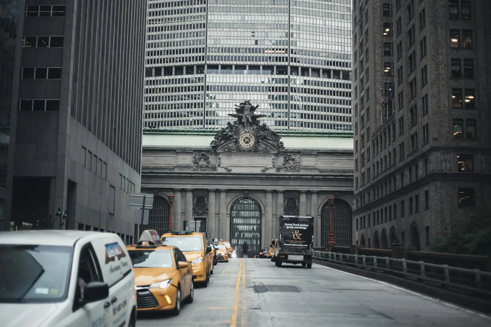 Siklista ida ho helmet no luz, nia sa'e bicycle iha estrada boot iha Nova York, ho tráfiku todan no prédiu aas iha kotuk, nia