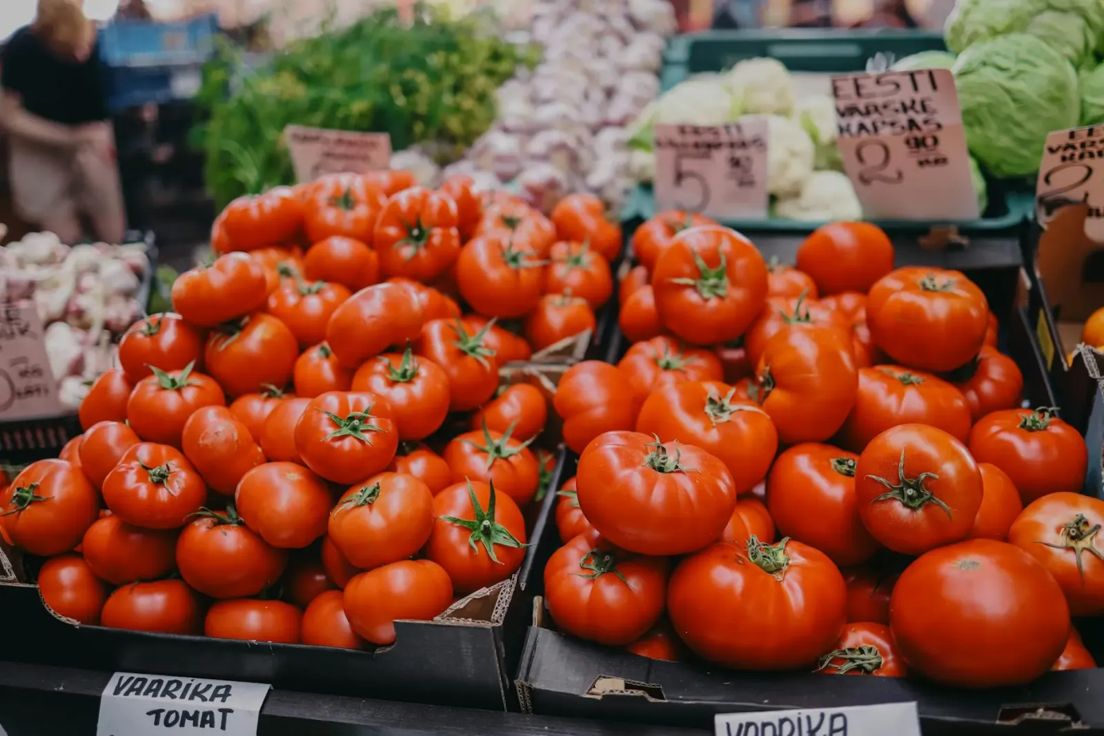 Imajen hatudu tomate sira iha loja, ho etiketa presu ne'ebé sa'e, hodi hatudu krise ekonomia no mudansa klimátika.