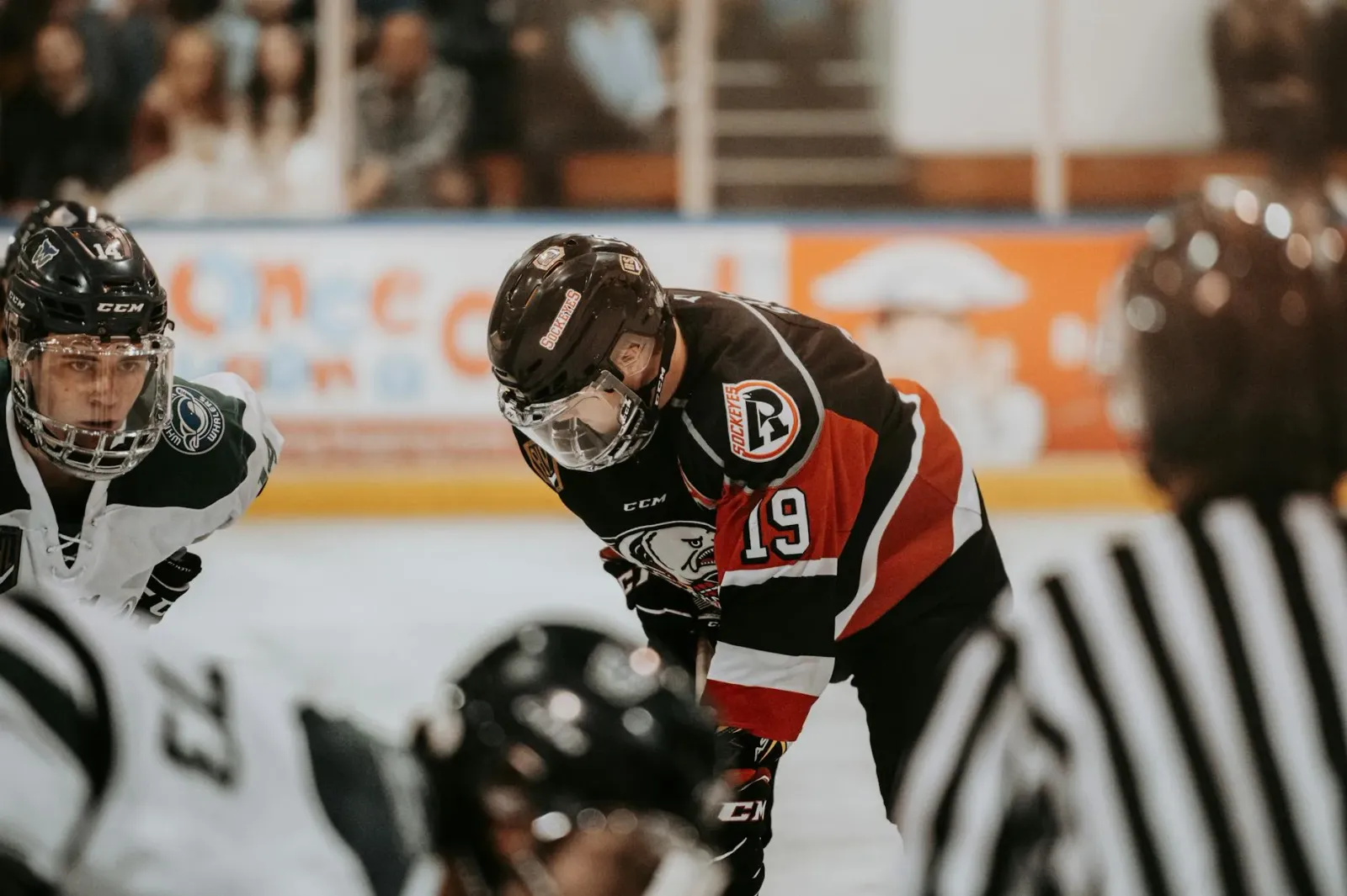 Jogadór NHL iha kampu ho kamuflada vermelhu no brancu, torcedor sira iha tribuna hodi haree partida final entre Vegas no Caro