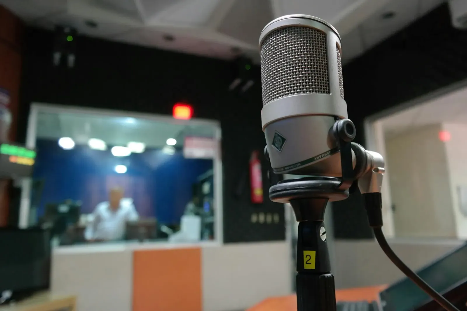 Ema rua koalia iha estúdiu rádio desportu ho imajen futebol kolejiu iha laran, hatudu atmosfera servisu profesional