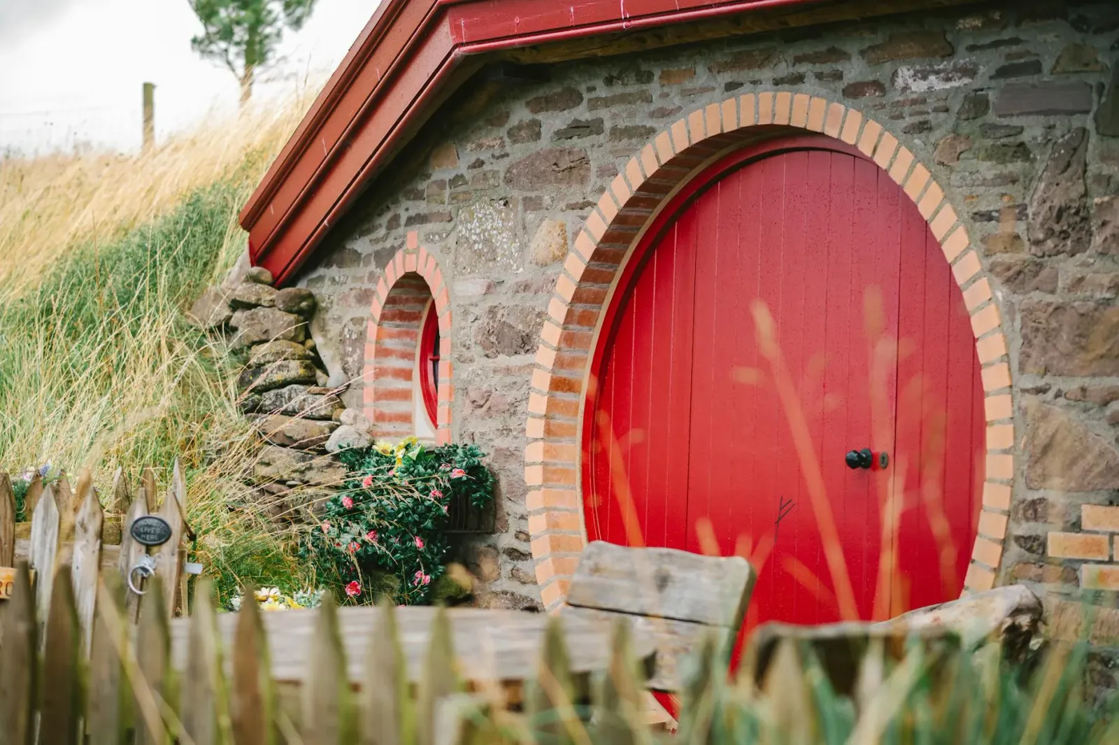 Paisajen ida husi mundu 'The Lord of the Rings' ho uma ki'ik ne'ebé hanesan Bag End, iha campu verde no ai-fuan boot iha lara