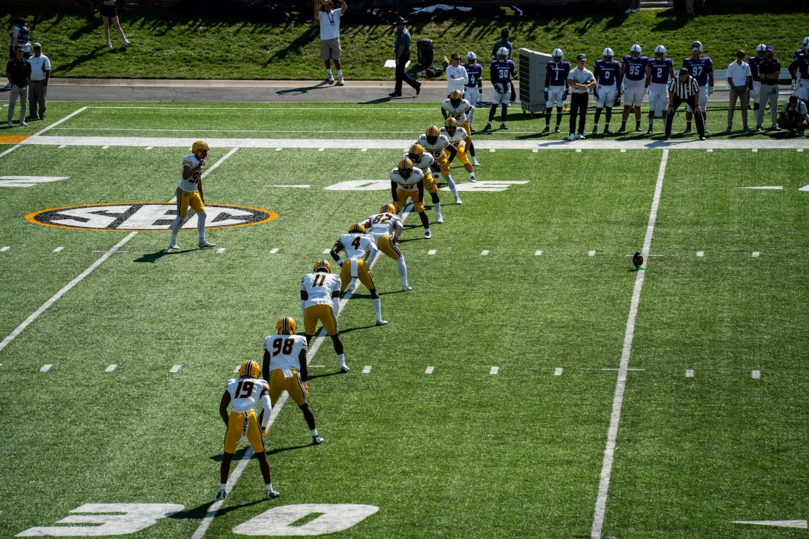 Jogadór LSU Tigers iha kamuflaje jogu kontra McNeese State iha estadio, ho torcedor barak iha fundu, hatudu emosaun no intens
