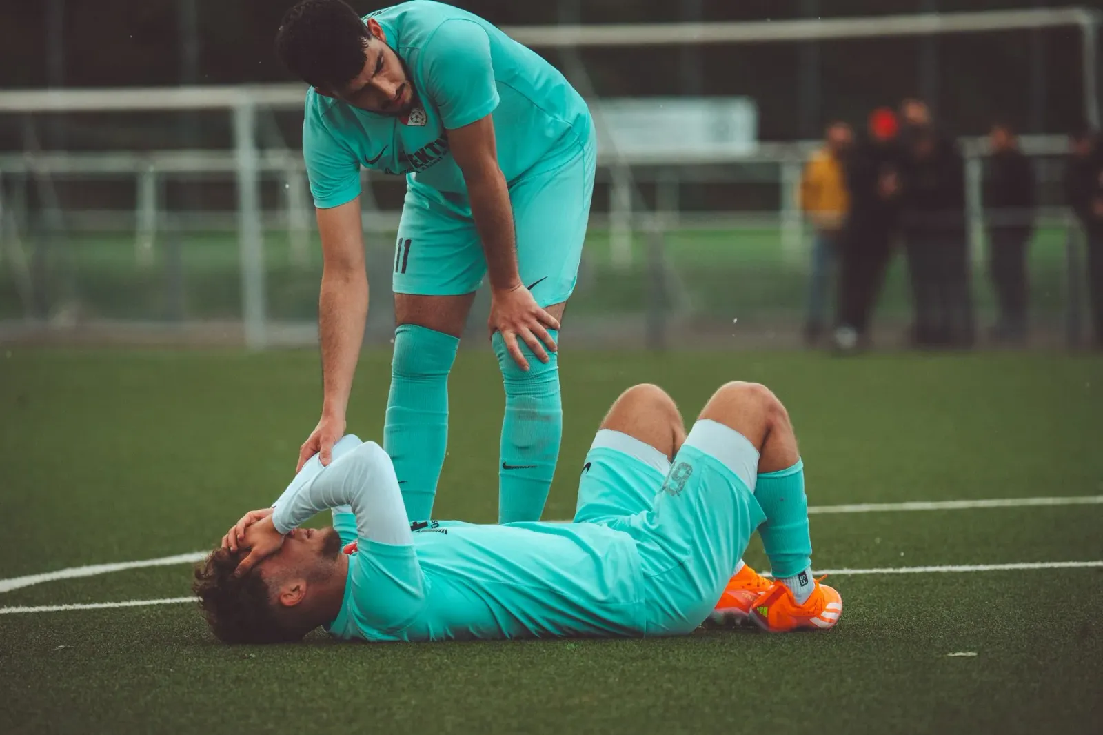 Christian Eriksen kolapsa iha kampu futebol, ekipa médiku ajuda nia, iha estádiu nia laran, ho bandeira Dinamarka iha kotuk.