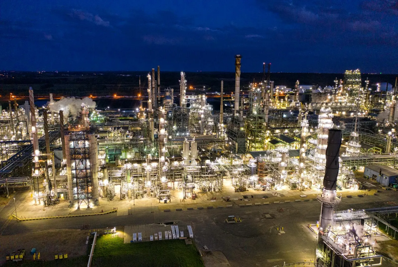 Imajen ida hatudu unidade refinaria petróleu boot ho tanque mina no tubu komplikadu, iha laran kmaan, ne'ebé reprezenta prose