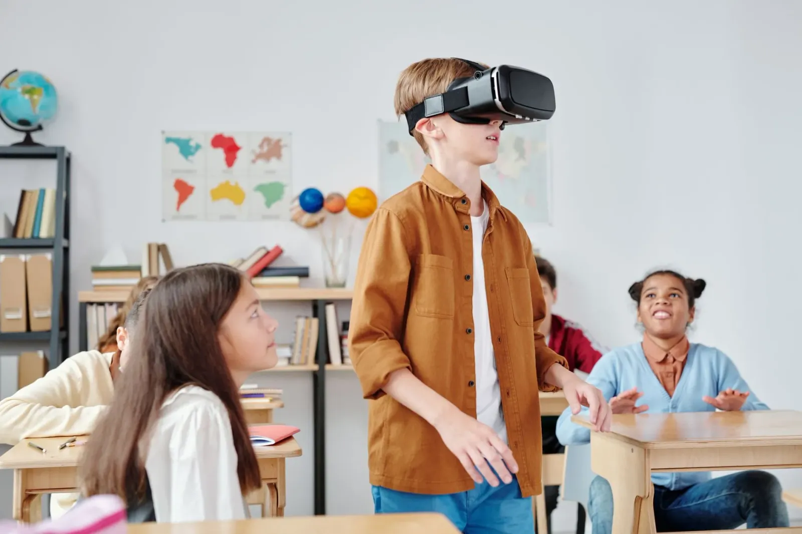 Imajen ida hatudu AI glasses no labarik sira uza telefone iha eskola, ho fundo sala aula ne'ebé hatudu desafiu privasidade no