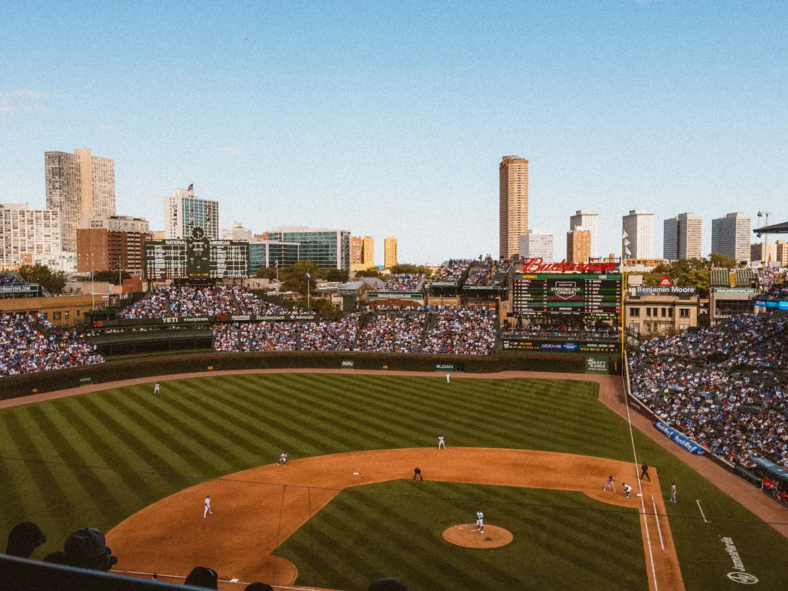Imajen estadiu beisebol Chicago Cubs ho jogador sira iha jogu kontra Rockies, hatudu atmosfera desportu nian