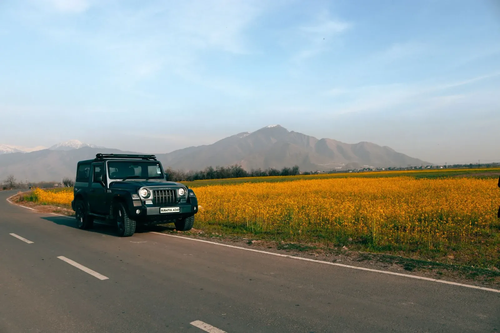 Família husi Timor-Leste viajen iha estrada ho karreta Mahindra, ho paisajem foho iha kotuk