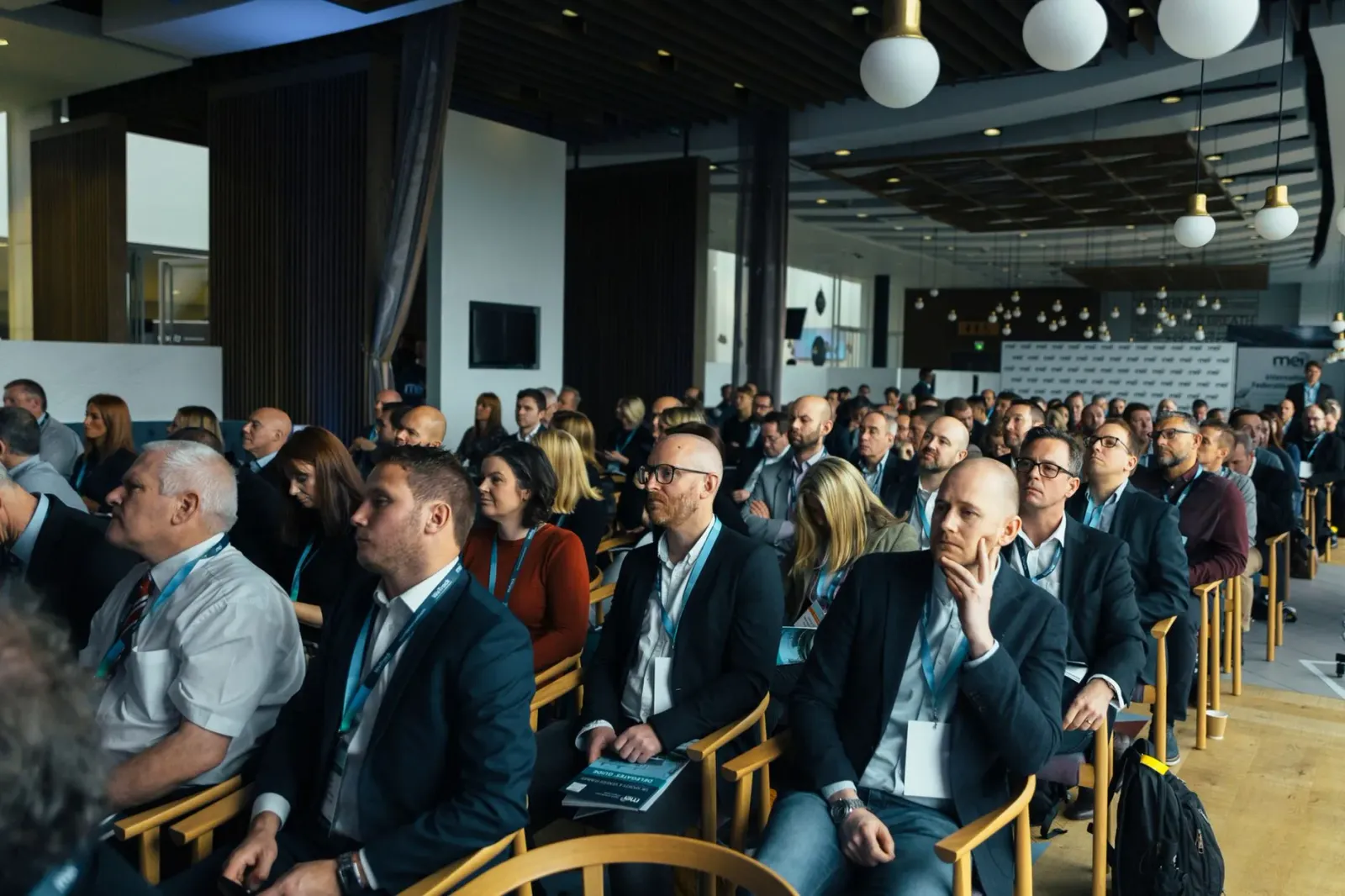 Imajen ida ne'ebé hatudu eventu konferénsia teknolojia espasiál ho ema barak hamutuk iha sala boot, ho projetór hatudu satéli