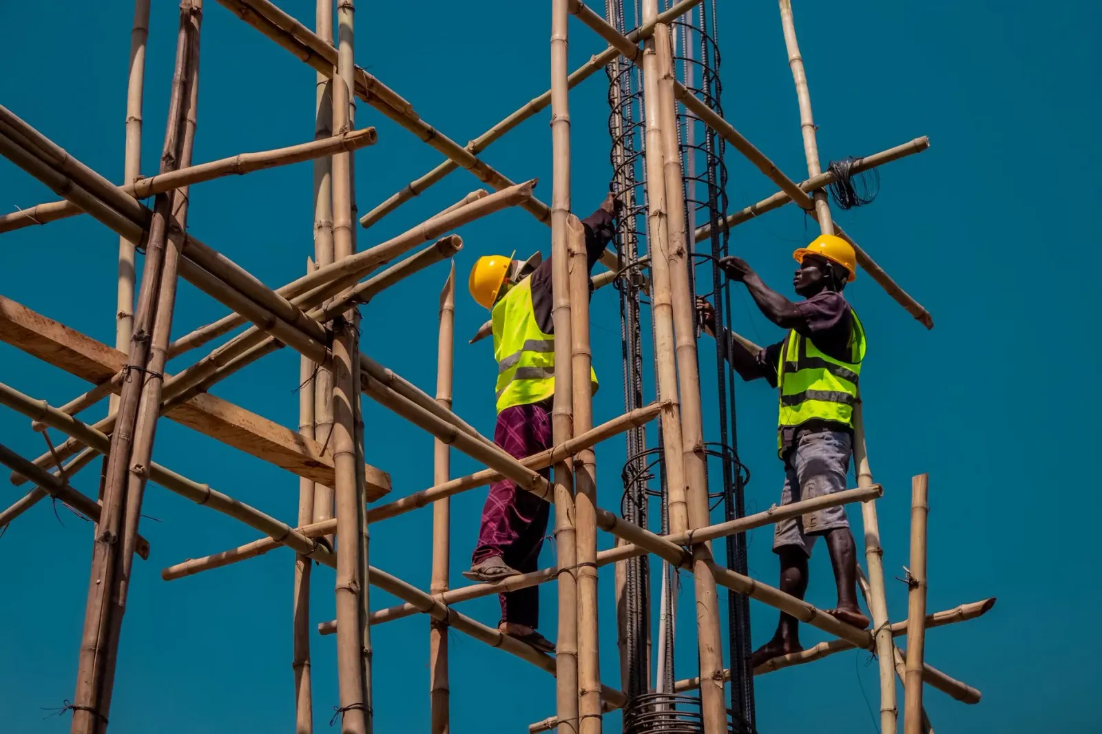 Imajen hatudu obra konstrusaun data center ho scaffold boot no enjineiru sira halo servisu, ne'ebé refleta tema pivot negósiu