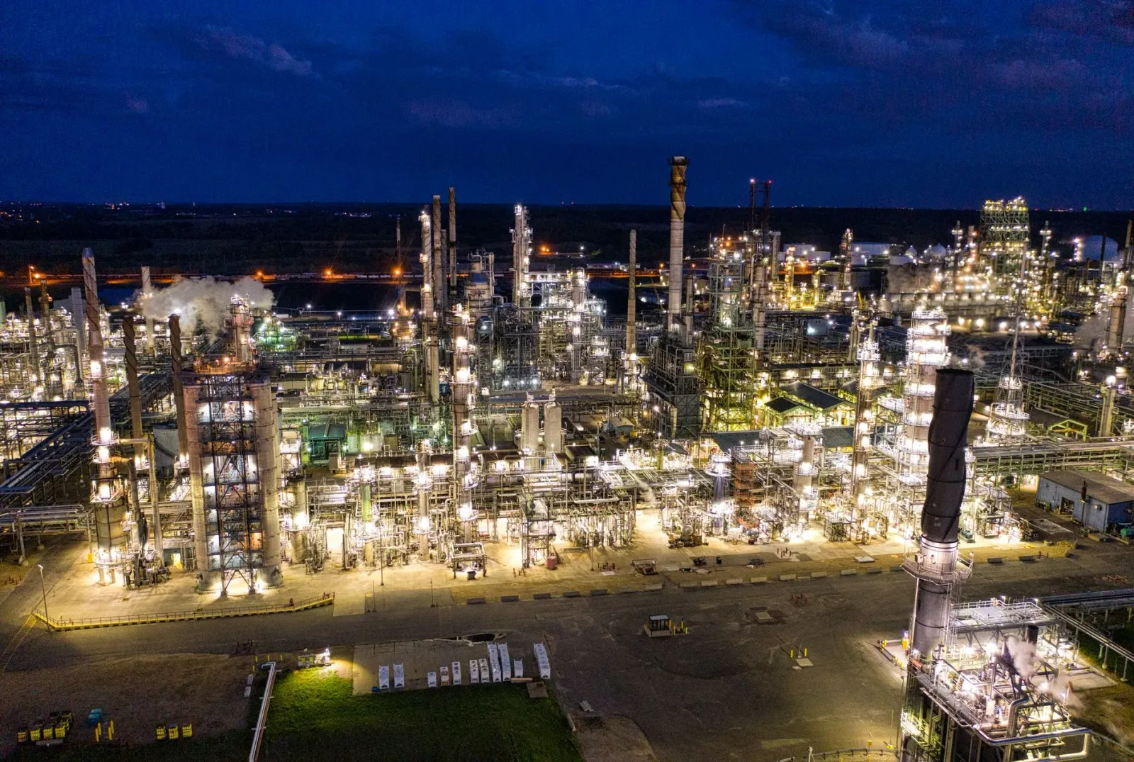 Imajen ida husi refinery minirai boot iha USA ne'ebé hatudu tanque minirai no fumaça, simboliza mudansa husi USA sai vendedor