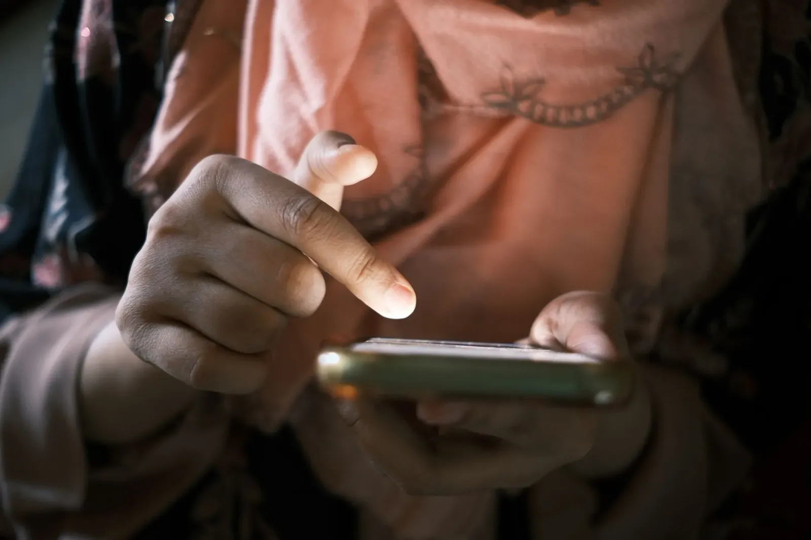 Ema ida hela iha sofa, hodi scrolling liu husi ekrã hanesan telefon, ho sorrisu iha rosto, no fundu ne'ebé kalmadu ho livru n