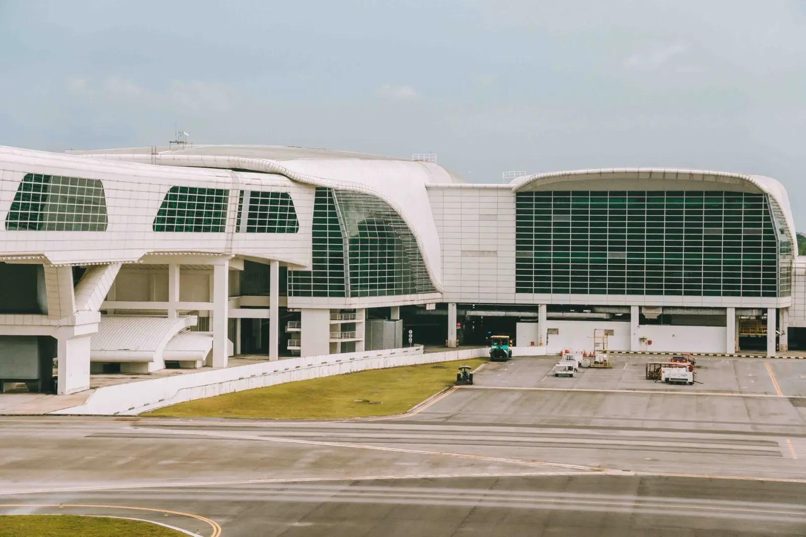 Imajen husi edifísiu terminal aeroportu Noida Internacional ne'ebé modernu, ho aviaun iha pista no konstruksaun kontinua.