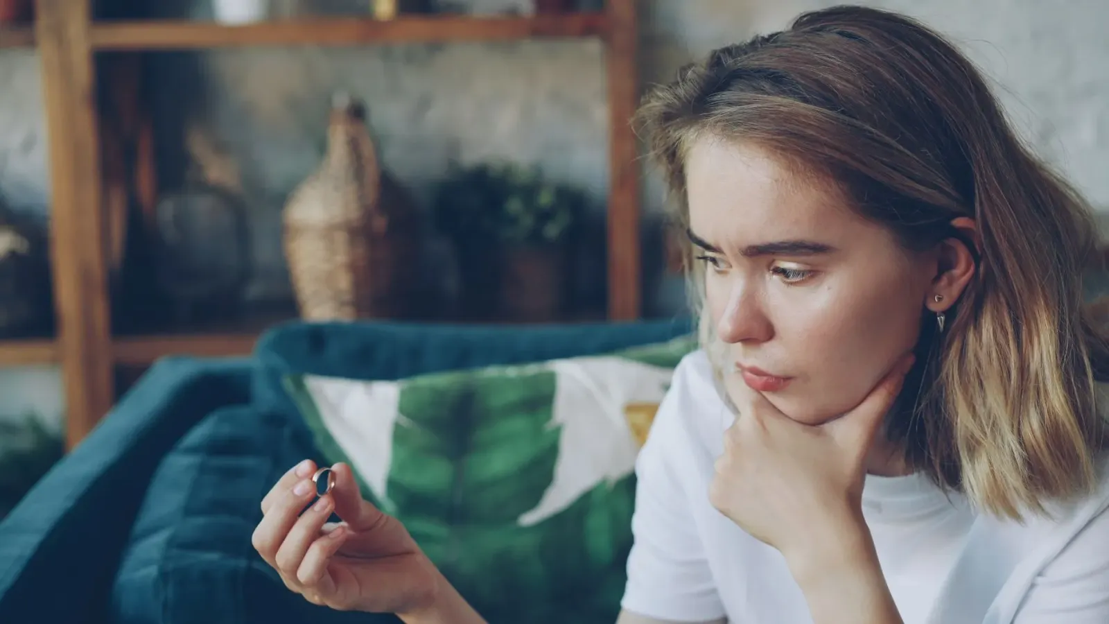 Ema ida tuur iha meza, hanoin kona-ba fiar no faktu, ho livru no figura psikolójia iha parede