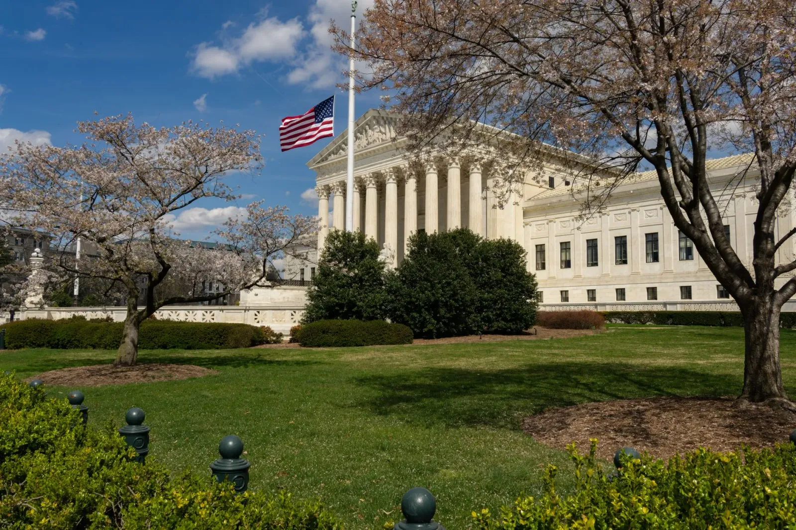 Imajen edifísiu U.S. Supreme Court iha Washington D.C. ho bandeira americana iha leten, hatudu podér judisiál ne'ebé influéns