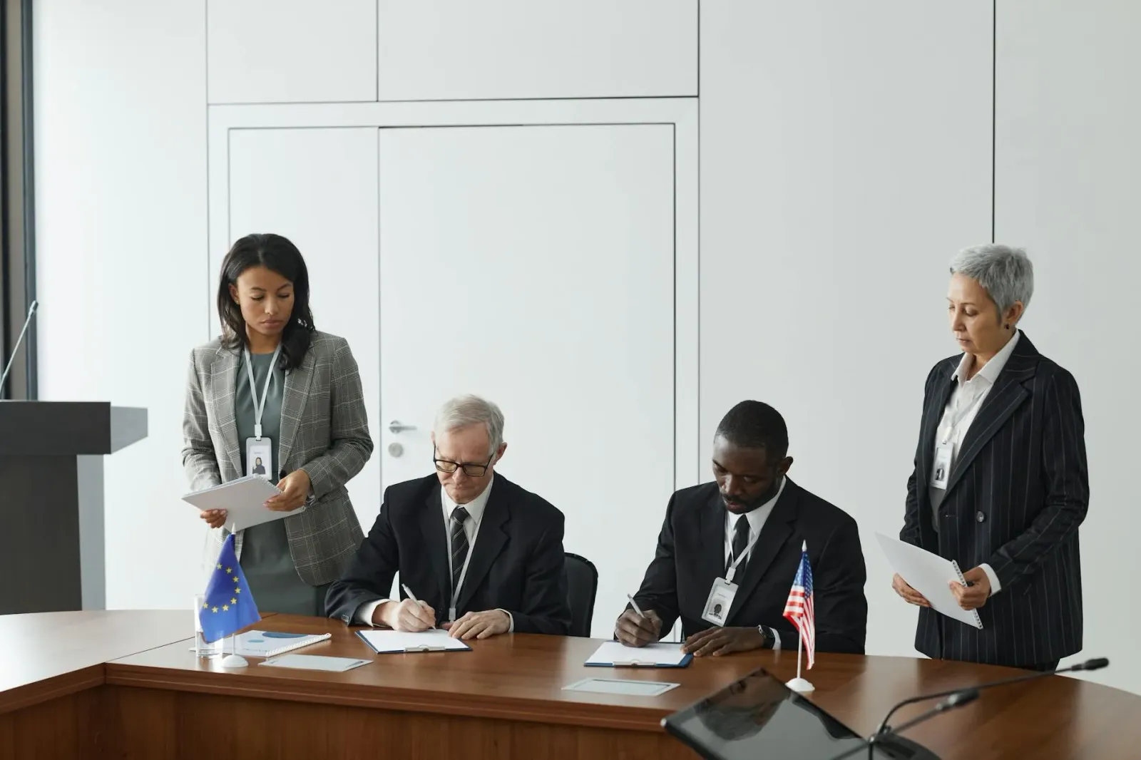 Imajen hosi reuniaun governu ho lider negósiu sira diskute regulasaun foun iha meja boot ho dokumentu no laptop