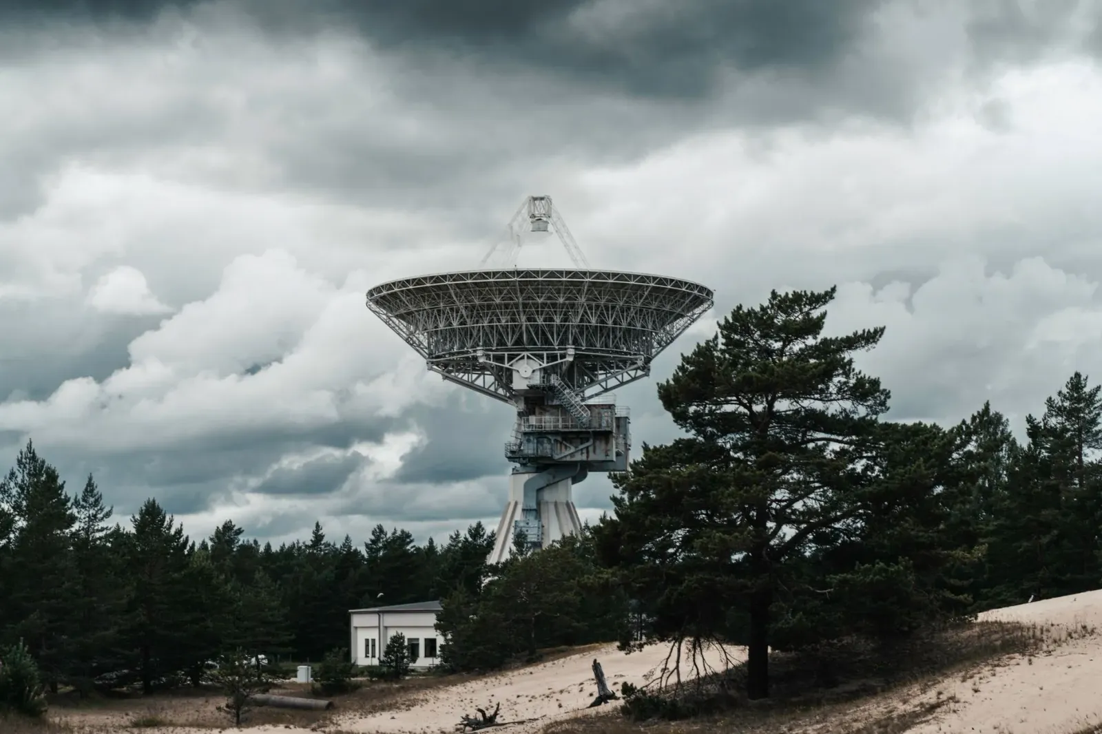 Imajen hatudu infraestrutura AI: data center ho komputador barak, radar previsaun clima, no ema uza ChatGPT iha laptop atu so