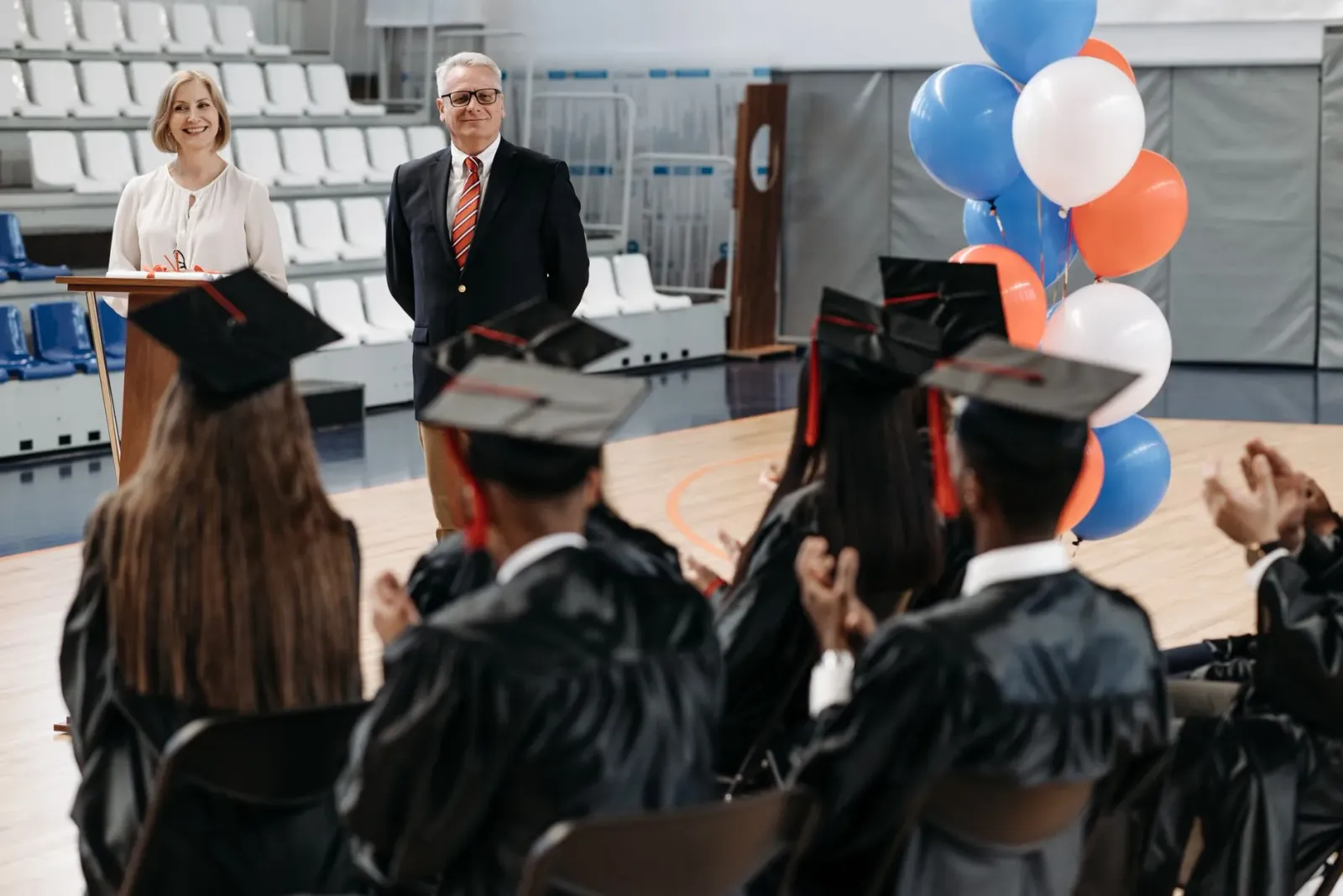 Imajen husi serimónia graduasaun iha universidade, ho estudante sira boos ba oradór ne'ebé koalia kona-ba AI.