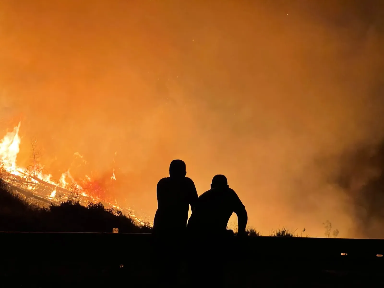 Imajen hatudu fogo lahan boot iha Idaho besik estrada Interstate 90, ho asaun ema evakuasaun no bombeiru kombate fogo, ilustr