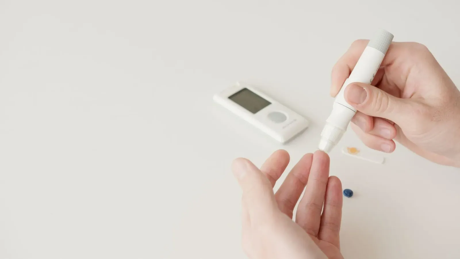 Ema ida ho liman uza glucometer atu kontrola nia asukar rápidu, ho sorrisu iha rosto, iha ambiente luminosu no saudável