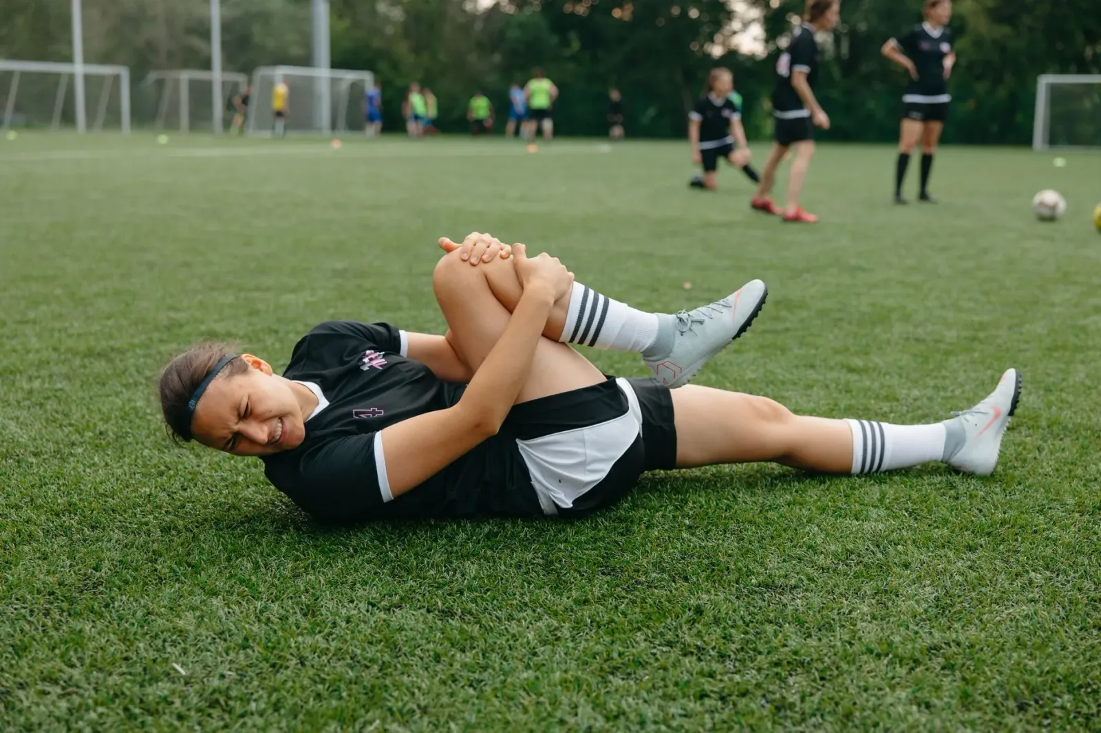 Imajen ida hatudu Cam Skattebo, jogador futebol americano, ho kanek iha tornozelu, nia hein iha kampu, ho uniforme New York G