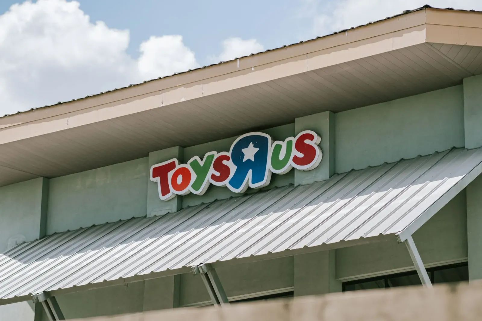 Imajen ida hatudu loja brinquedu Toys R Us no loja kafé Starbucks iha area komersial, ho ema sira la'o hela, simboliza mudans