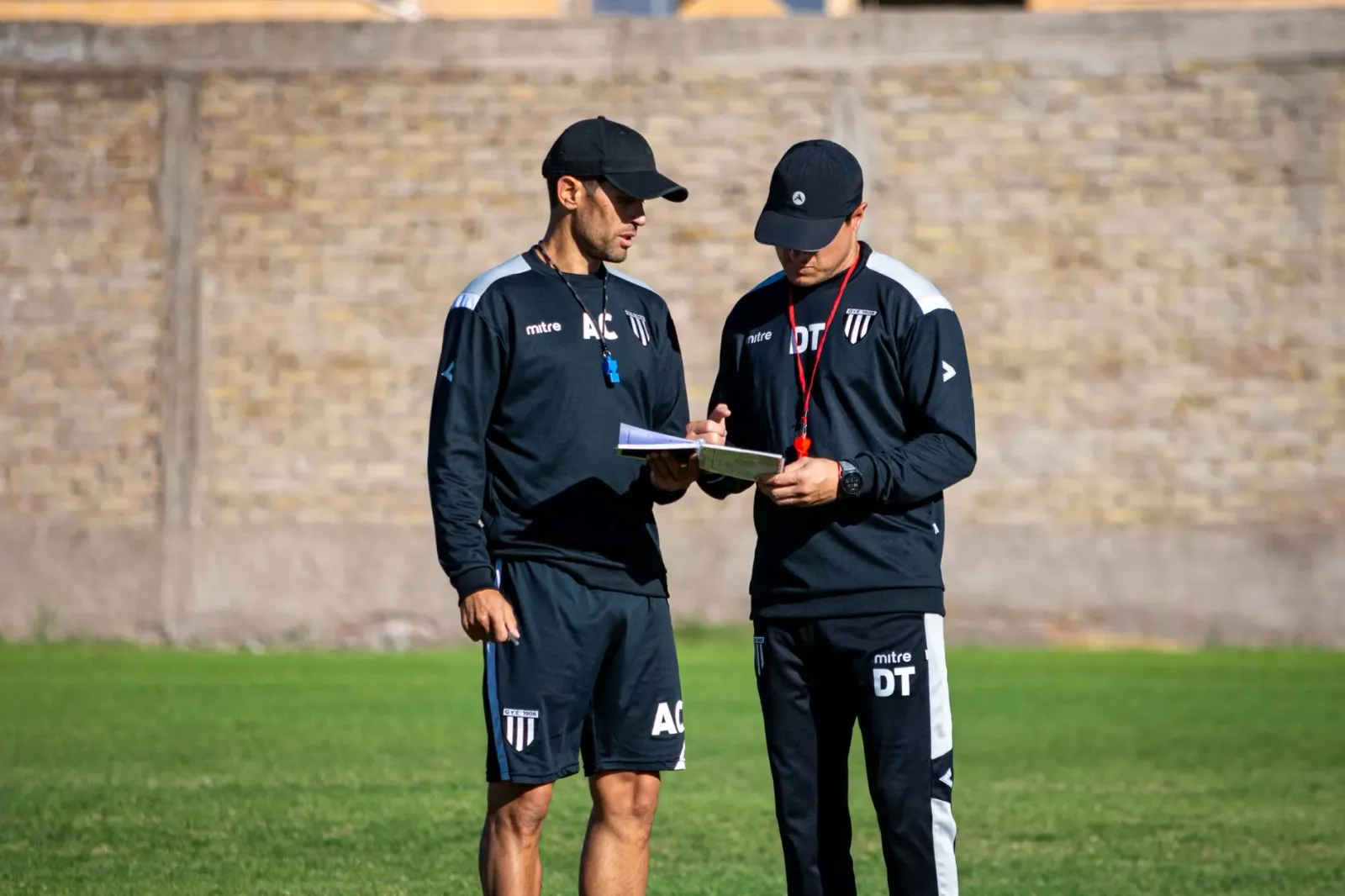 Treinador futebol ida hatudu estratégia ba jogador sira iha kampu, ho bola no tátika desenha iha quadru