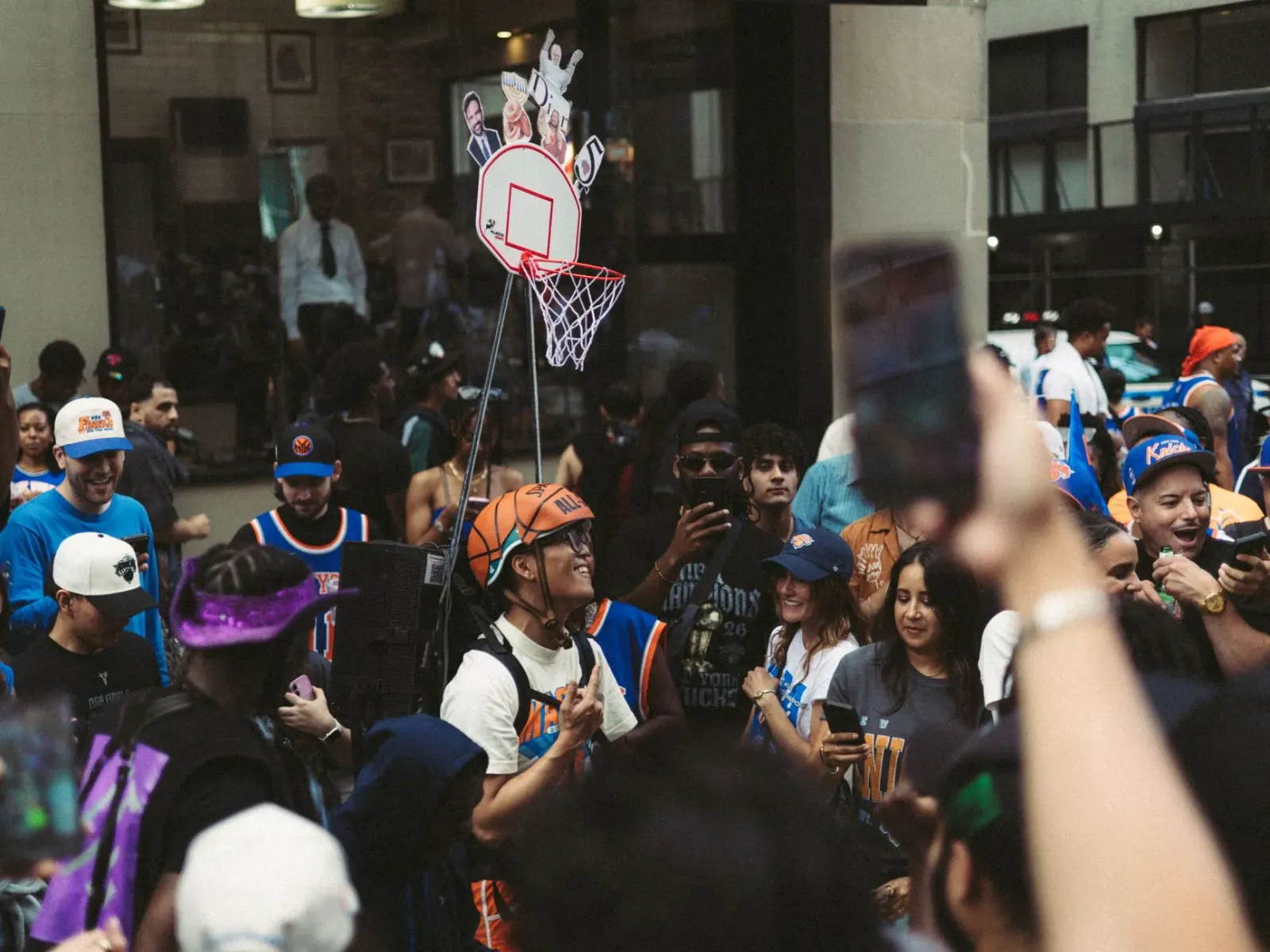 Fã diversu husi New York Knicks iha jogu basketball, hatudu fã lesbiana no ema husi grupu diferente sira sorriso no aplaude