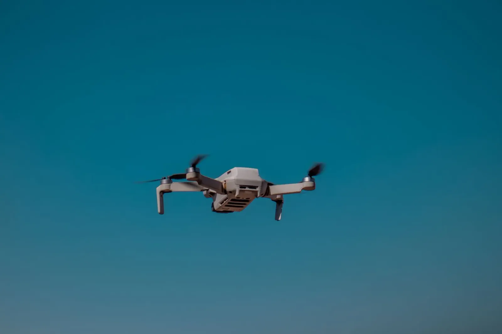 Imajen ida ne'ebé hatudu drone submarinu AUKUS iha tasi laran, ho luz azul no infraestrutura kabu submarinu, hodi ilustra tek