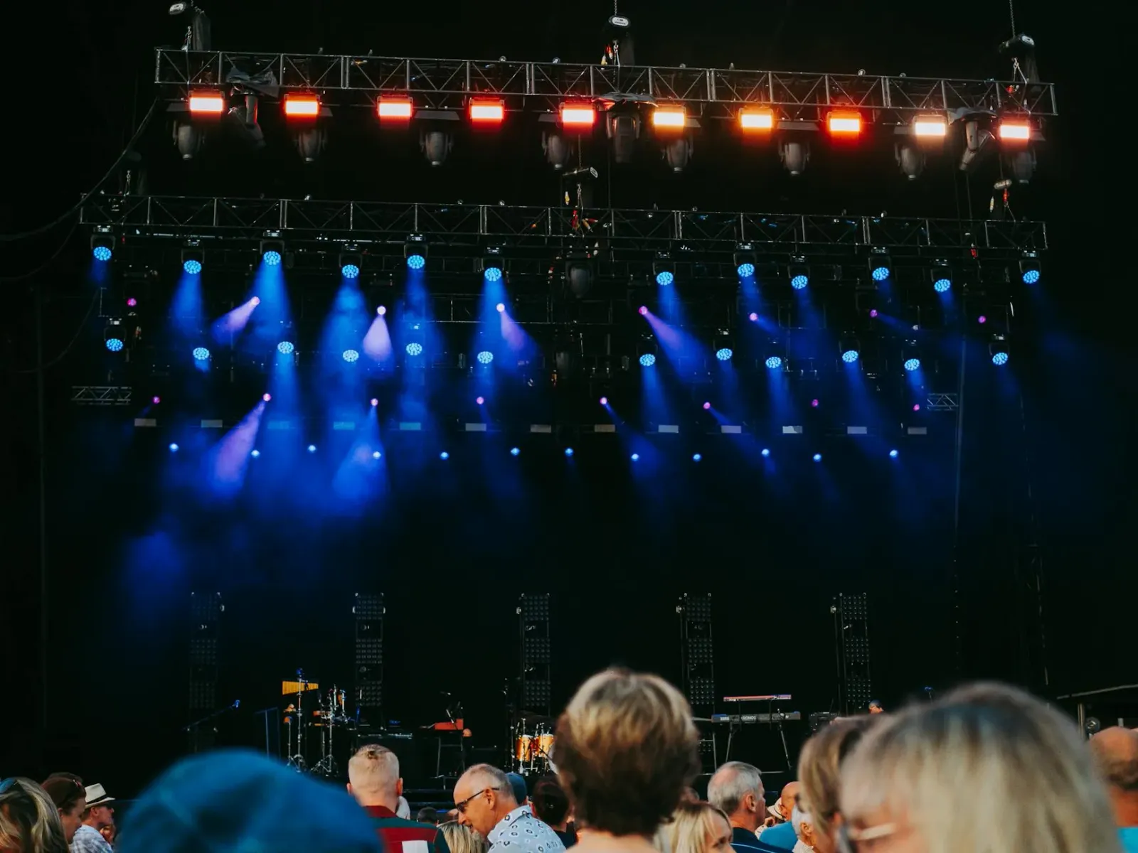 Multidão animada iha eventu entretenimentu ho luz no palco boot, hatudu atmosfera festiva maibe mós hatudu risku potensial ho