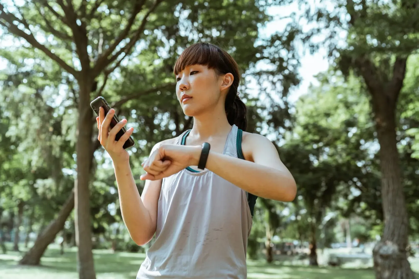 Ema ida uza fitness tracker iha liman durante korre iha natureza, ho monitor smartwatch hatudu dadus treinu no GPS