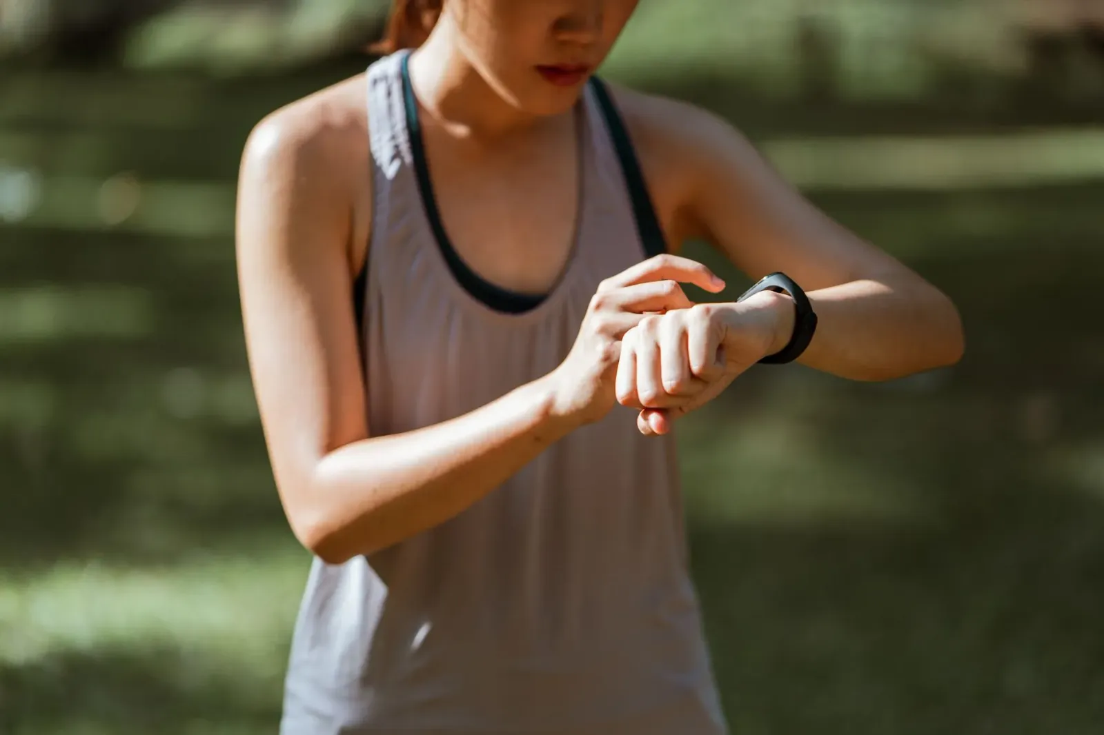 Atleta profisionál uza fitness tracker iha nia liman durante treinu iha estádiu, ho smartwatch Garmin no Fitbit iha nia liman