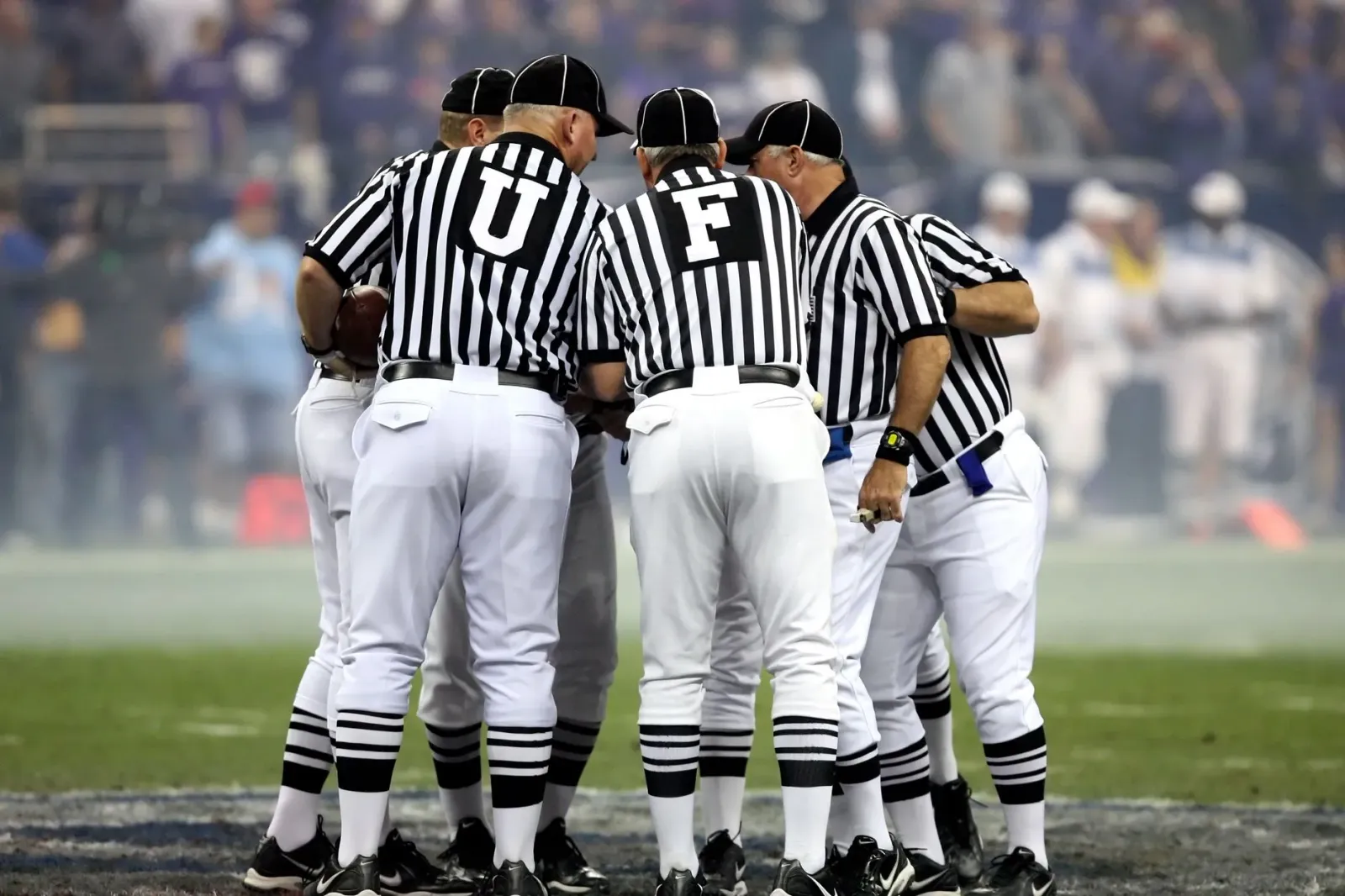 Ema barak iha estádiu NFL sira haree ho atensaun ba jogador sira no árbitru iha kampu, hatudu oinsá desportu liga malu ho jus
