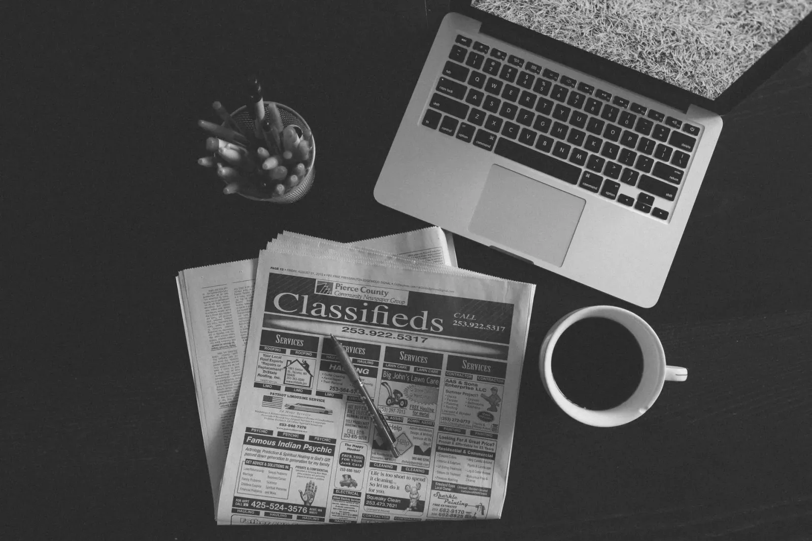 Ema ida lee notísia negósiu iha laptop ho kafé iha meja, simboliza analiza informasaun finanseiru