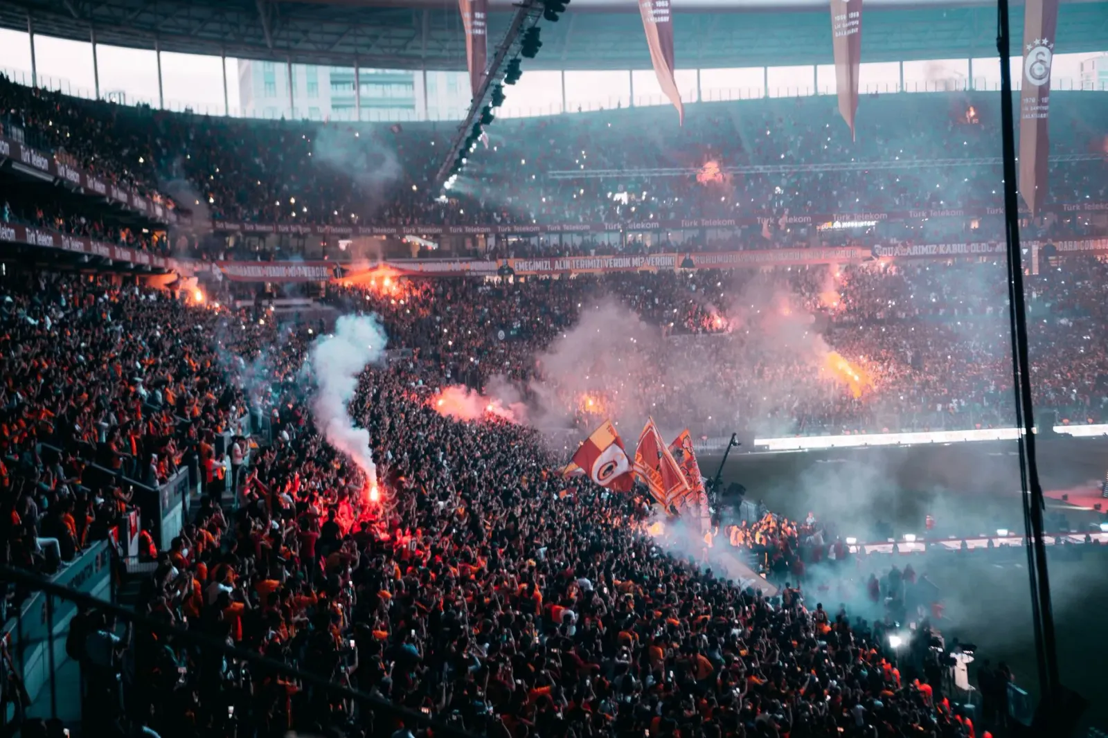 Imajen ne'ebé mostra grupo e maun feto iha arena desportu, ho luz boot no atmosfera movimentu, representa mudansa boot iha mu