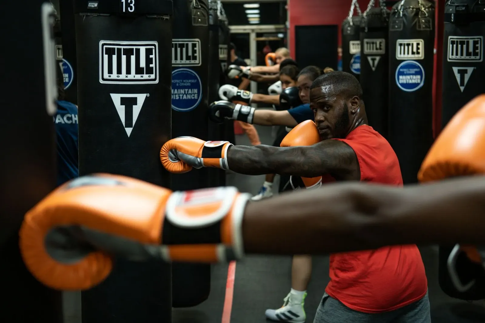 Floyd Mayweather Jr. hamriik iha ringue ho luvas boxe, nia rosto seriu, iha fundu luz neon, hatudu luta exhibition kansela ta