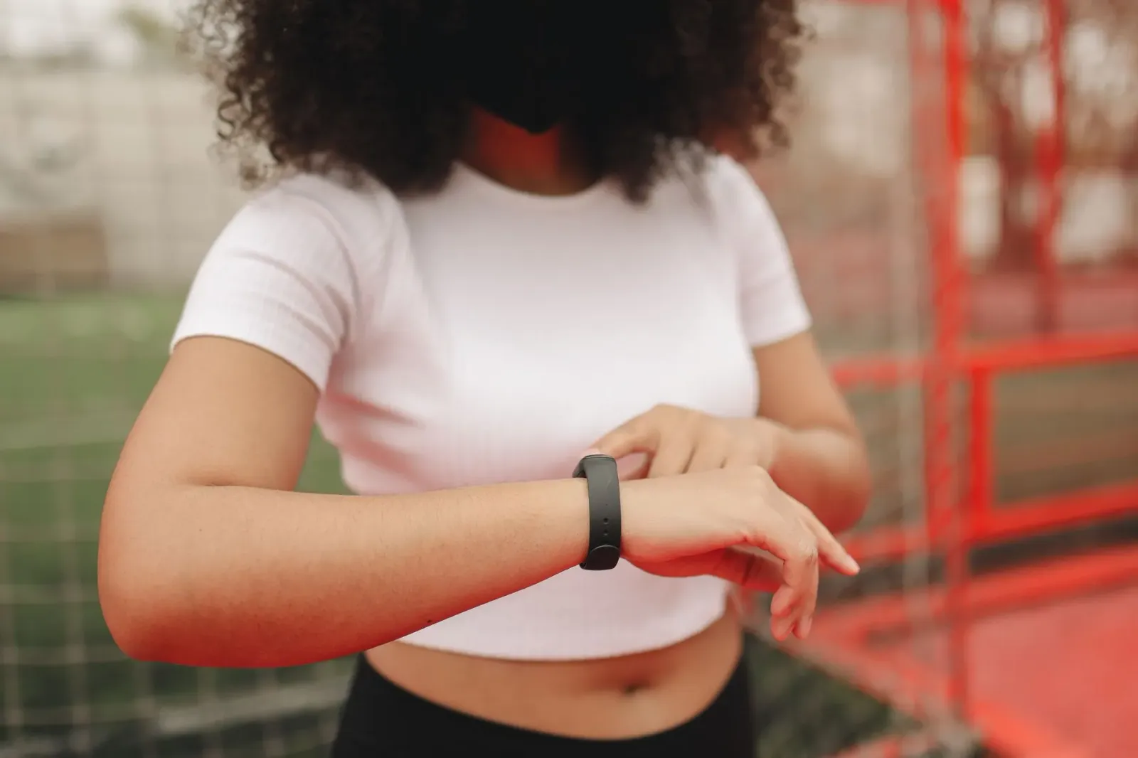 Atleta ida uza fitness tracker iha liman no hare jogu desportu iha televizaun ho Fire TV, iha uma treinu, ho sorrisu, ilustra
