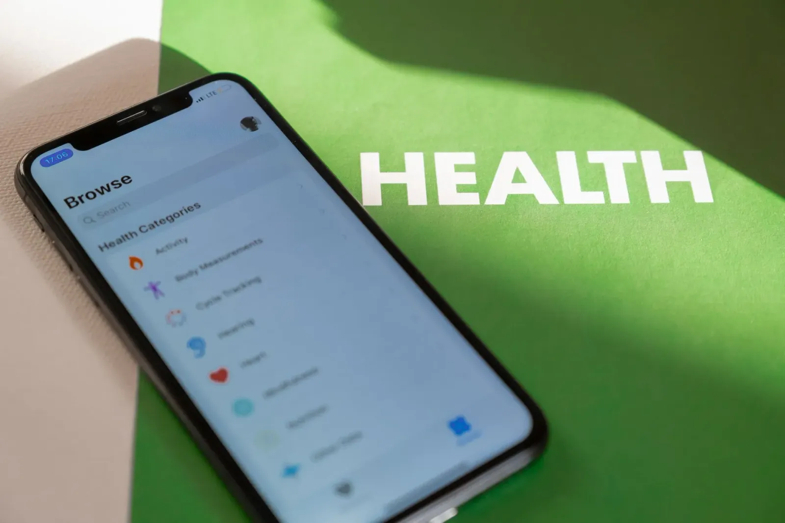 Ema ida uza smartphone ho aplikasaun saúde iha liman, iha futar alérjia no garrafa alkoól iha mesa, ho avizu risku kanser