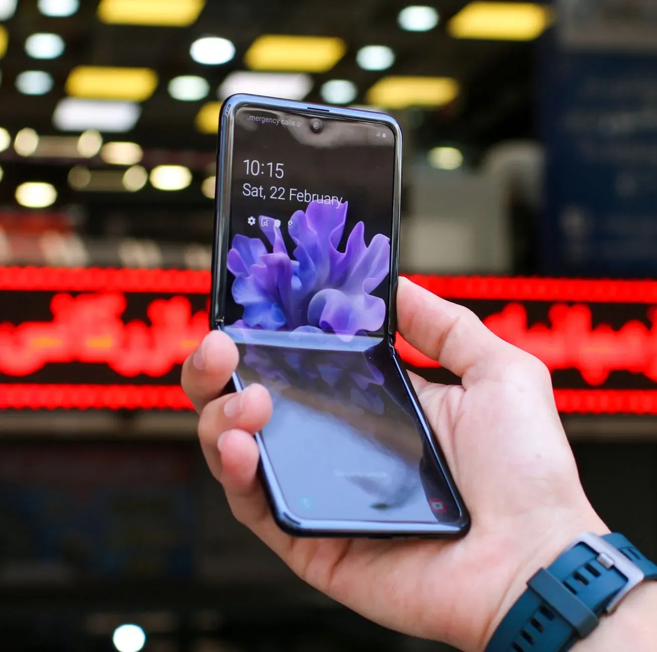 Ema uza Samsung Galaxy Z Fold 8 ho ekrã dobra, hatudu teknolojia foun iha ambiente servisu. Iha meja, dokumentu no kafé, simb