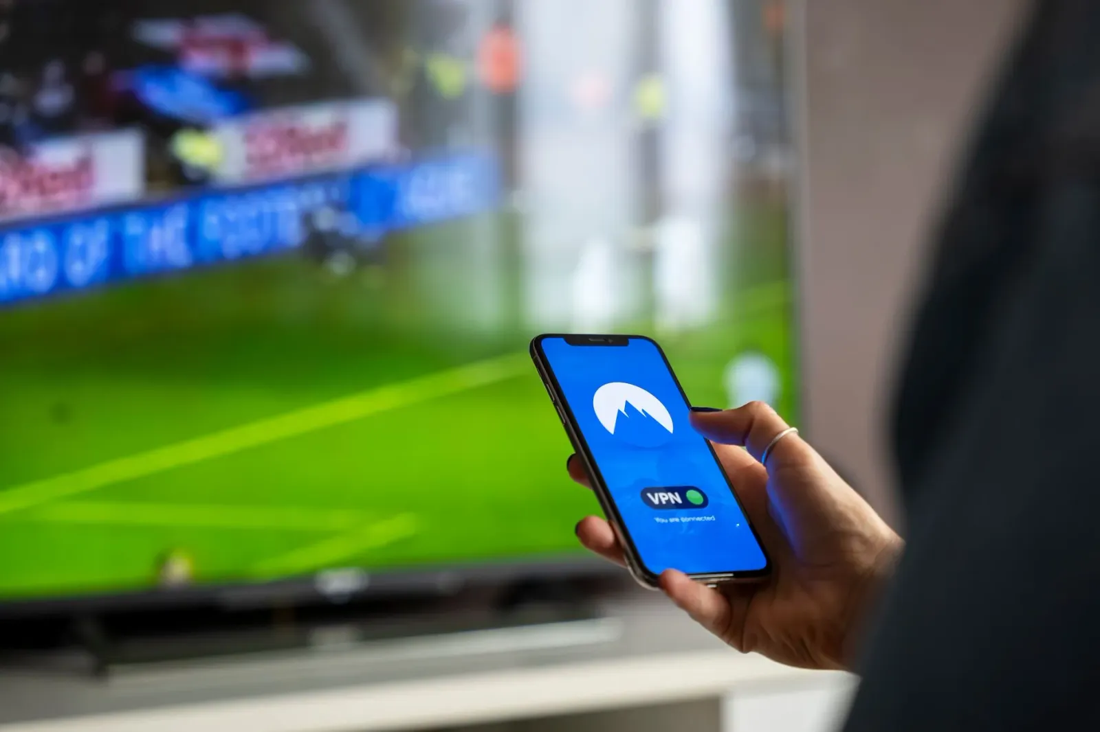 Imajen hanesan pessoa boot uza smartphone atu haree kontenidu entertenimentu iha sala, ho luz neon ne'ebe halo ambiente futur