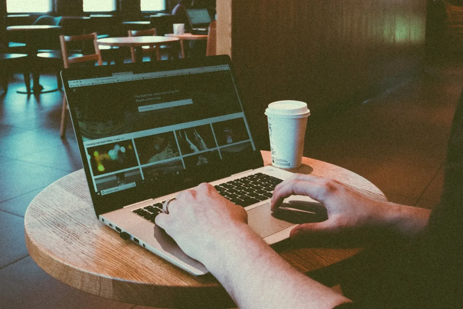 Imajen ida hatudu laptop ne'ebé iha ekrã web design, hamutuk ho kopu kafé no livru, iha meja ida iha kafé, hatudu ambiente se