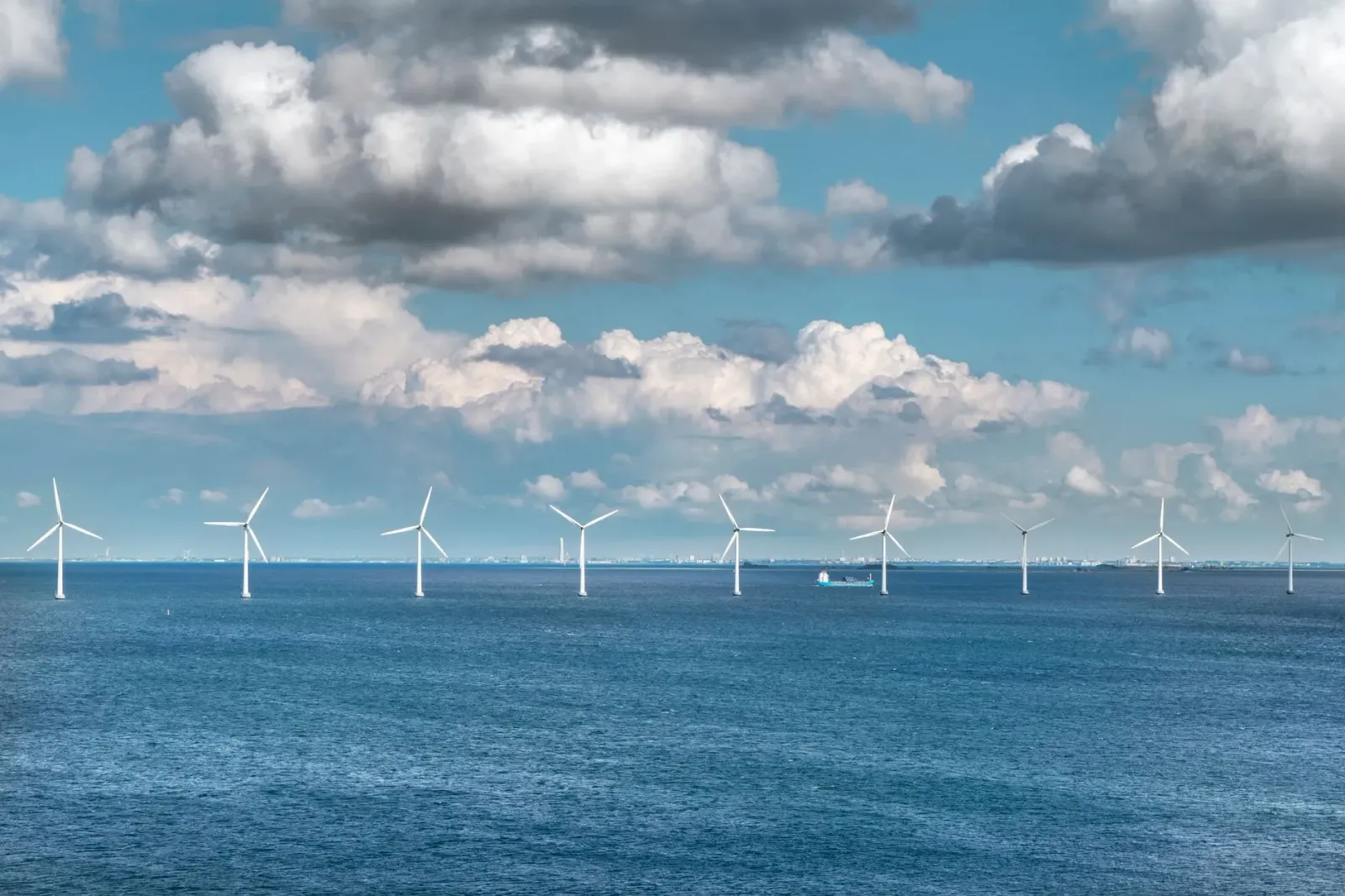 Imajen ida hatudu turbina ventu iha tasi laran ho kor azul no nuvens branca, reprezenta projetu ventu ne'ebé para tanba desiz