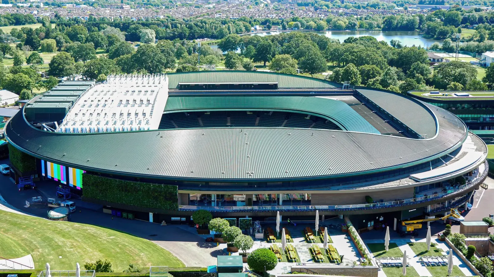 Imajen ida ne'ebé hatudu estadiu tenis Wimbledon iha rai laran, ho jogador sira jogu iha korti grama, ne'ebé reprezenta futur
