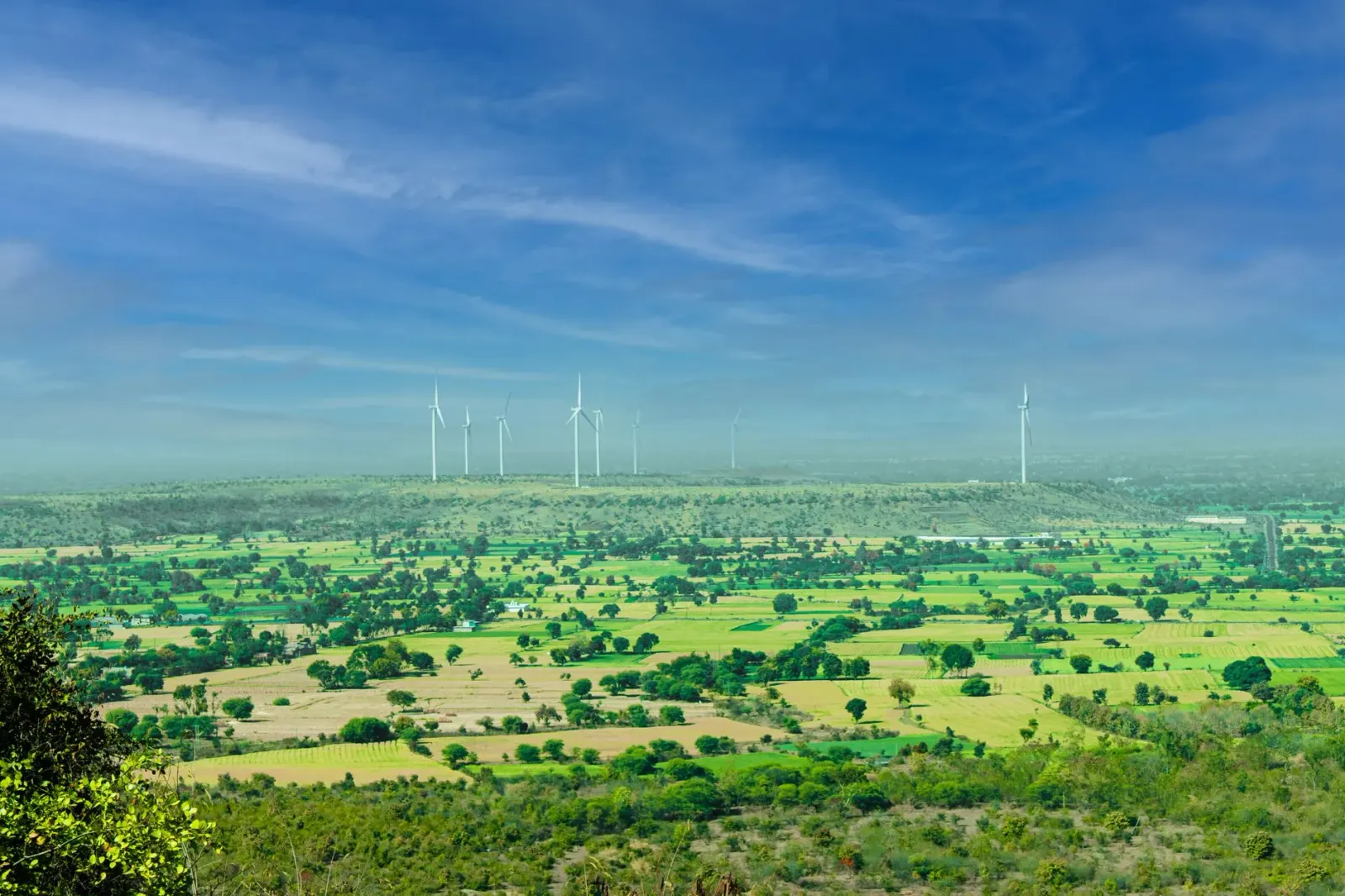Imajen hatudu projetu renovável iha India ho mudansa klima iha kotuk, hanesan painel solar no turbina anin iha paisajen ne'eb