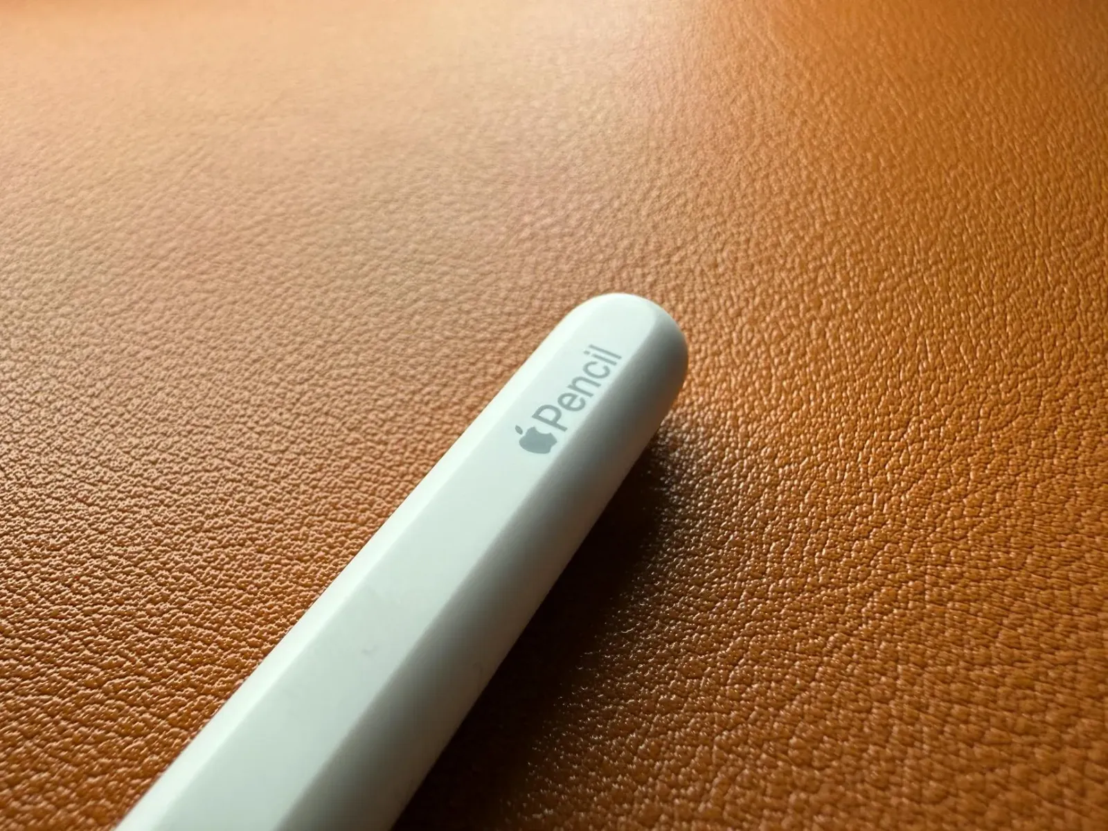 Imajen ida hatudu Apple Pencil ho tipu trokadu, ho fundu komputador no papel, atu ilustra teknolojia no konfiansa iha produtu