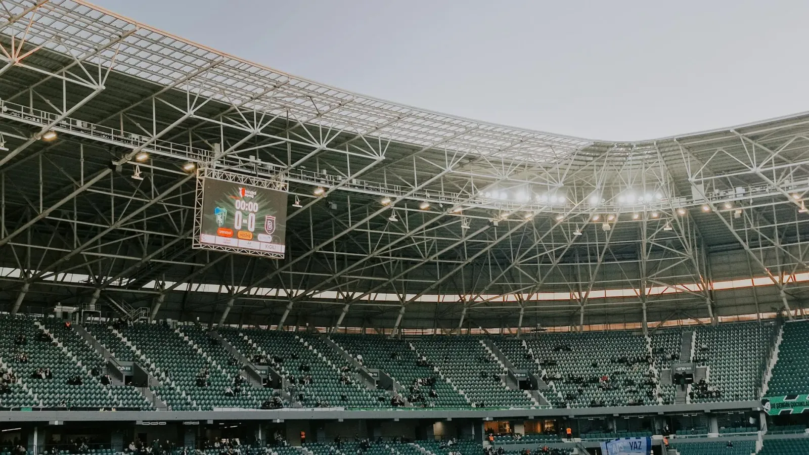 Imajen estadiu desportu universitáriu nakonu ho ema iha kalan, tuir luz boot, hatudu ambiente jogu futból amerikanu