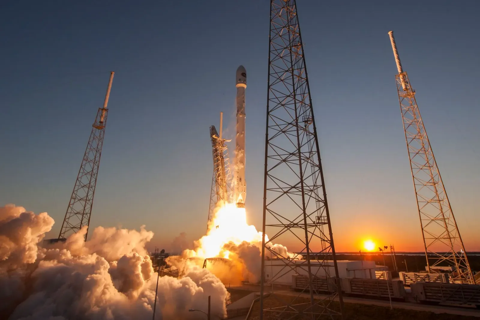 Imajen ida husi foguetu SpaceX lansa hela iha lalehan, ho fumu no luz boot, hanesan simbolu ba inovasaun teknolojia no invest