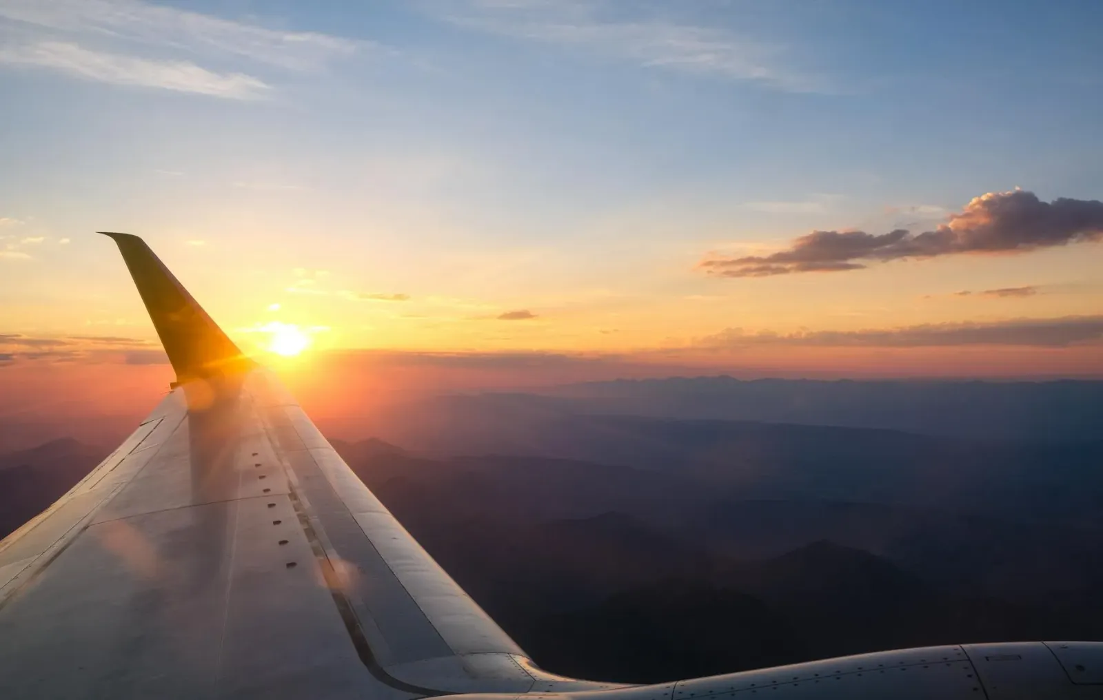 Ema ida haree hela aviaun iha aeroportu tempu loron monu, ho silueta feto ne'ebé haree ba aviaun boot, simboliza viajen no se