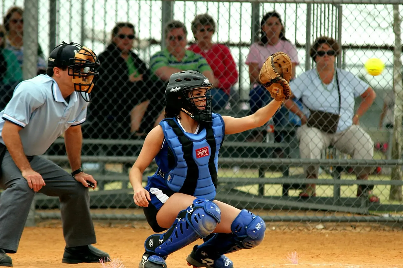 Jogador softbol luta iha partida importante, ho torcida iha kotuk, hatudu espíritu ekipa no kompetisaun