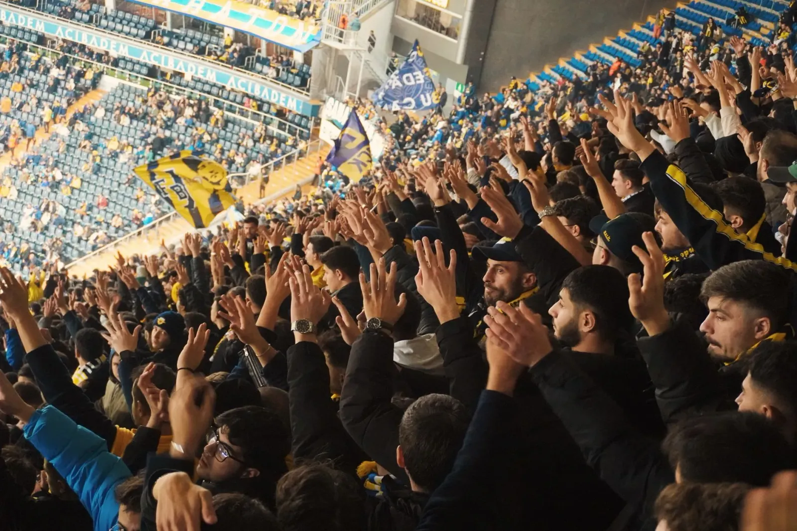 Ema barak iha estádio desportu, sira hamriik no haksoit tanba kontente, ho luz boot no bandeira sira iha kotuk, hatudu ambien